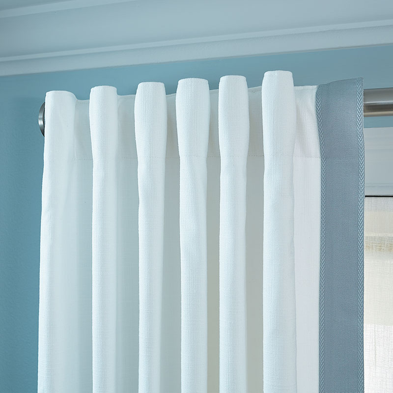 White custom non-pleated drapery with light blue vertical trim on silver hardware.