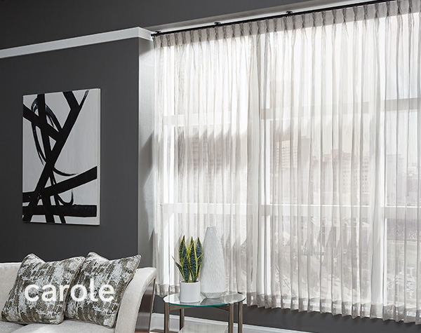 Medium grey living room with a wall of windows covered by sheer draperies with ceiling mounted drapery hardware.