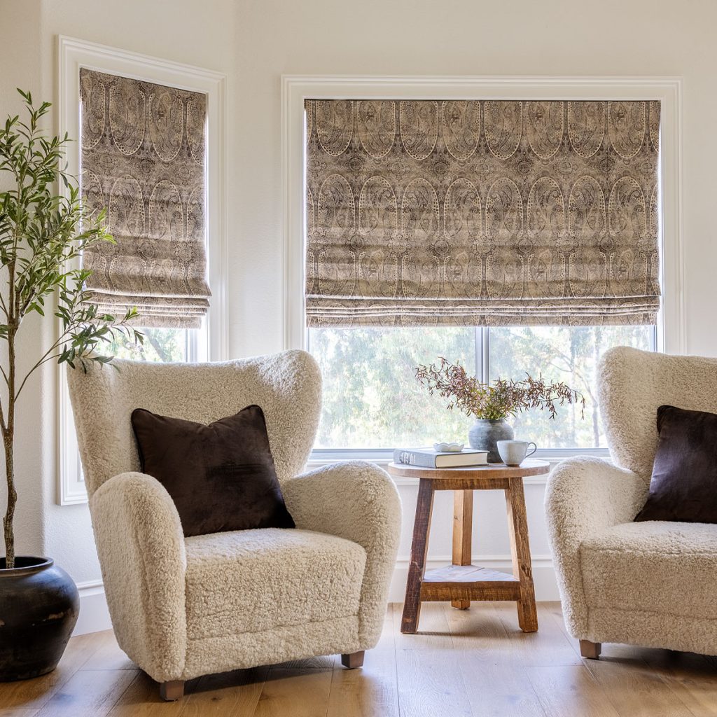 A sitting area featuring two windows with Flat Roman Soft Shades in a subtle tone on tone brown pattern.