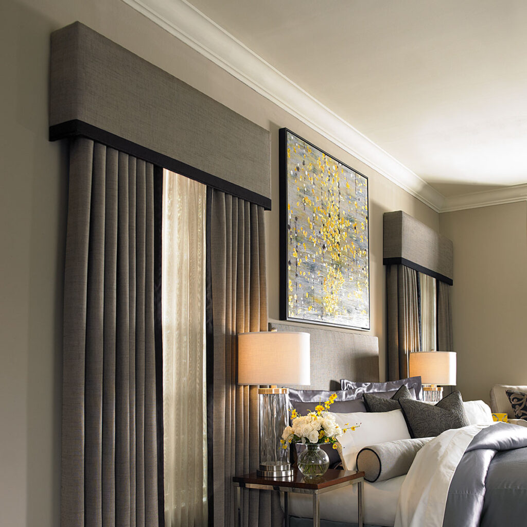 Statler Cornice top treatment in beige with black trim over Draperies in beige with black trim and ivory sheers in a dark neutral bedroom.