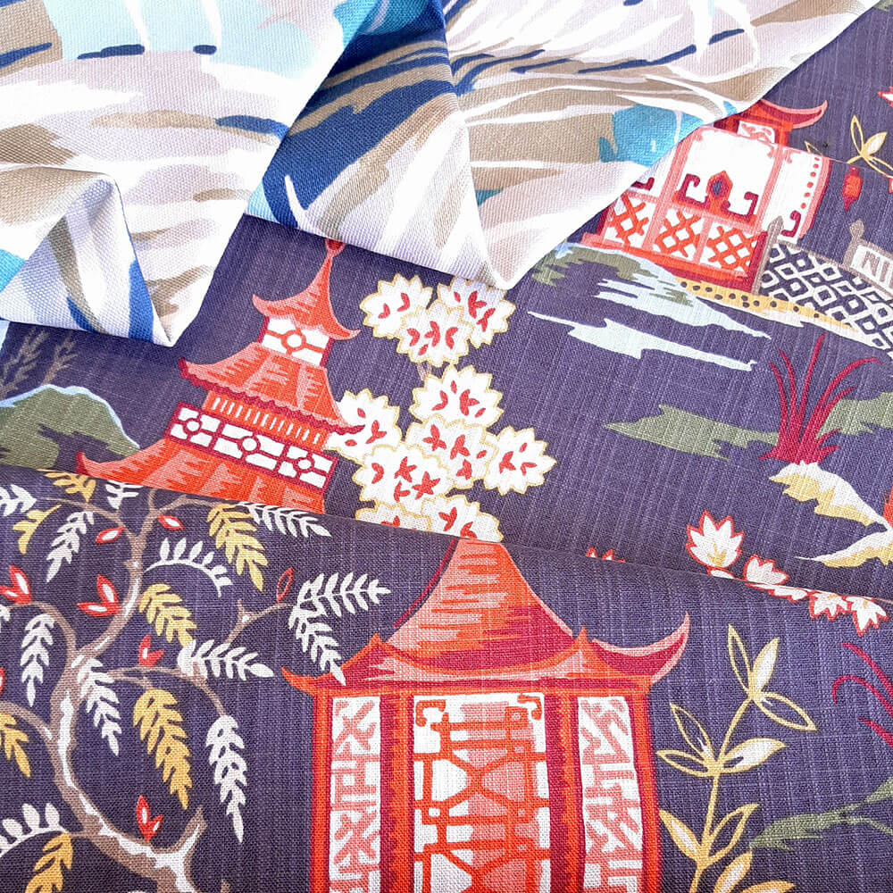 Two lightly folded print fabrics in a leafy blue pattern and an red on black pagoda pattern.