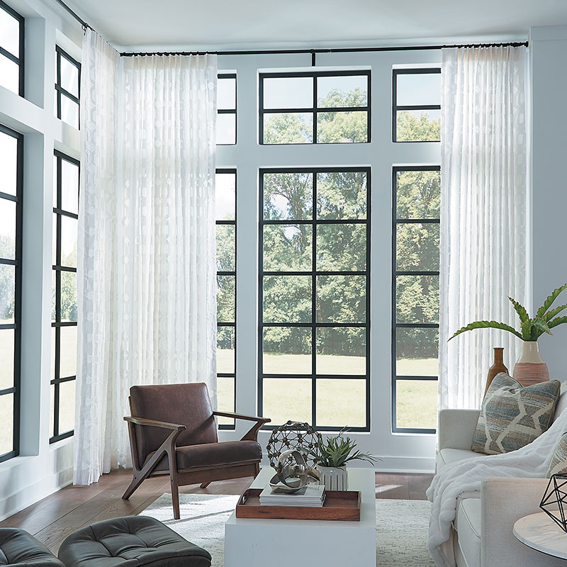 Floor to ceiling sheer draperies from Carole Fabrics in a sunroom.
