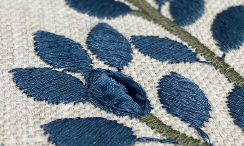 Detail of dark blue embroidery on a neutral background.